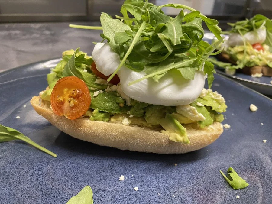 Smashed avocado, feta, tomato and poached egg on toast at Caffin8 Cafe