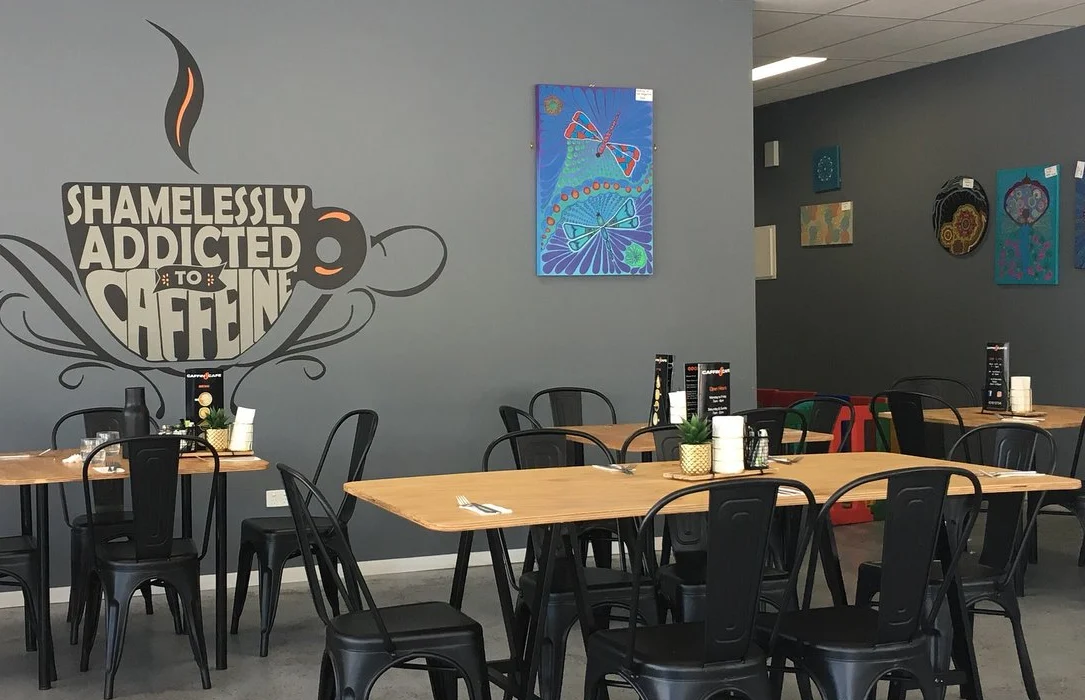 Caffin8 Cafe dining room with its coffee mural, timber tables and chairs