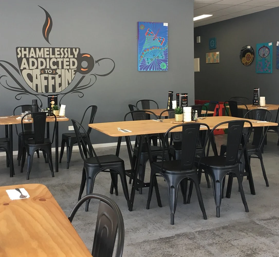 Caffin8 Cafe dining room with coffee mural, timber tables and black chairs